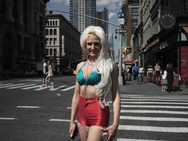 A color photograph of a woman vaguely dressed like a mermaid crossing the street.