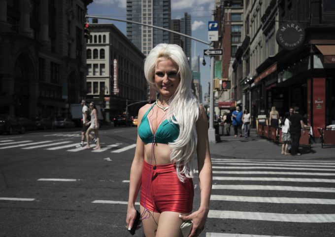 A color photograph of a woman vaguely dressed like a mermaid crossing the street.