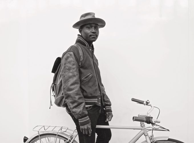A black and white photograph of a man on a bicycle.