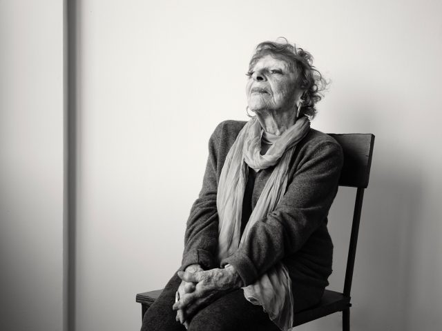 A black and white photograph of an older woman sitting in a chair.