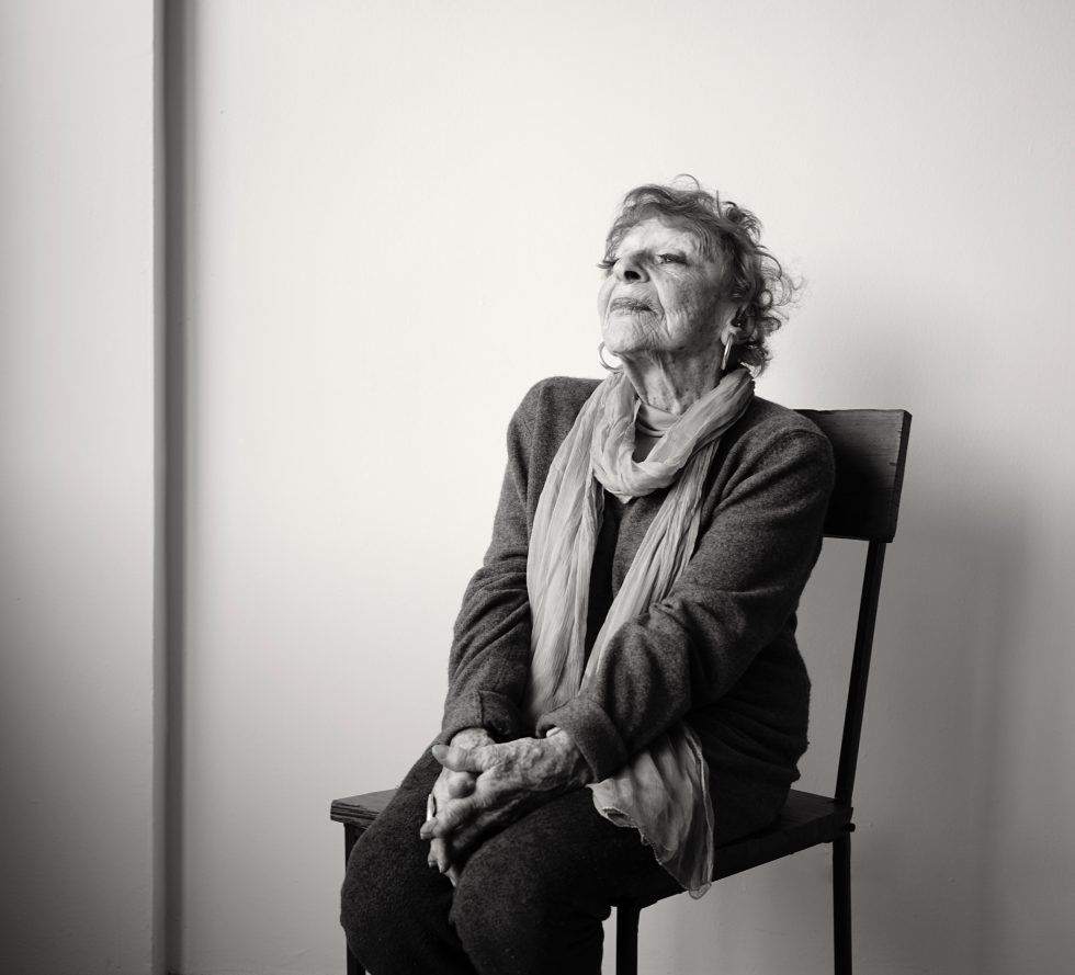 A black and white photograph of an older woman sitting in a chair.