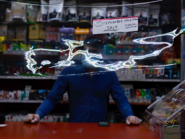 A photograph of a man behind a counter selling masks.