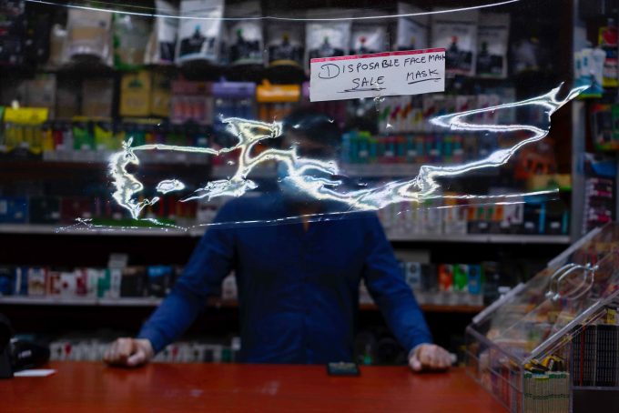 A photograph of a man behind a counter selling masks.