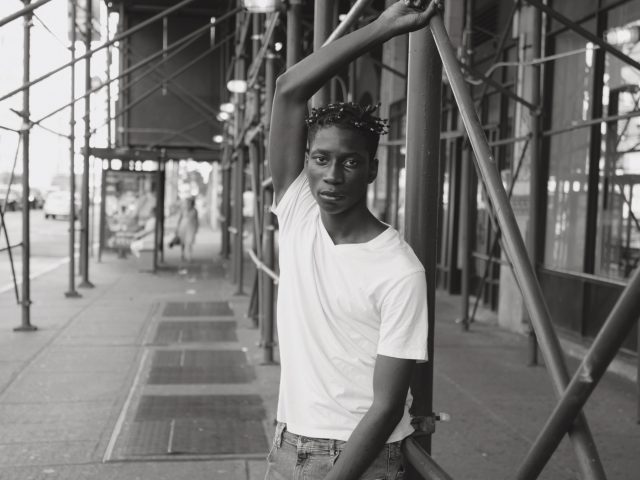 A black and white photograph of a handsome man under scaffolding.