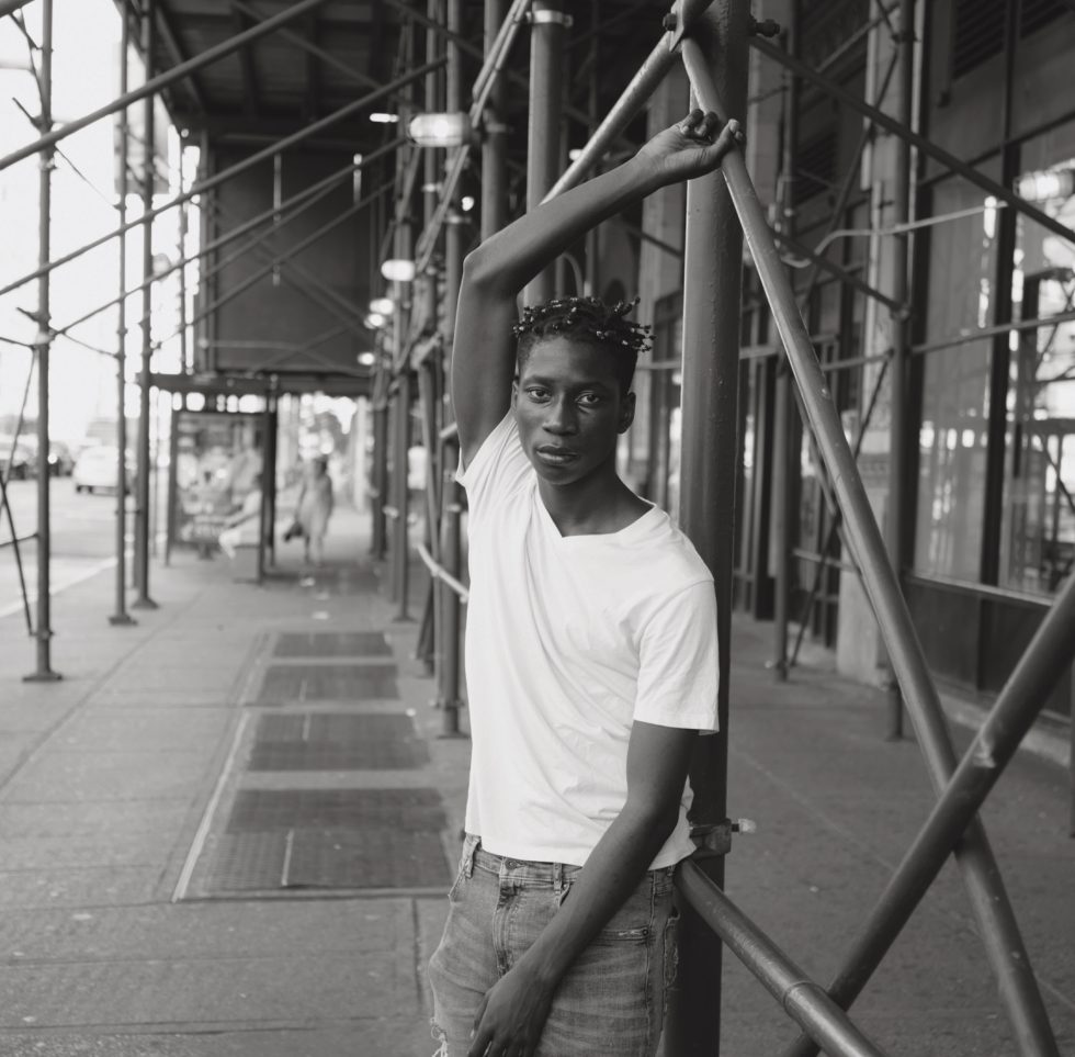 A black and white photograph of a handsome man under scaffolding.
