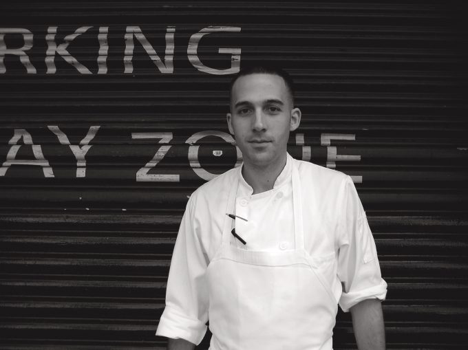 A black and white photograph of a cook having a cigarette outside.