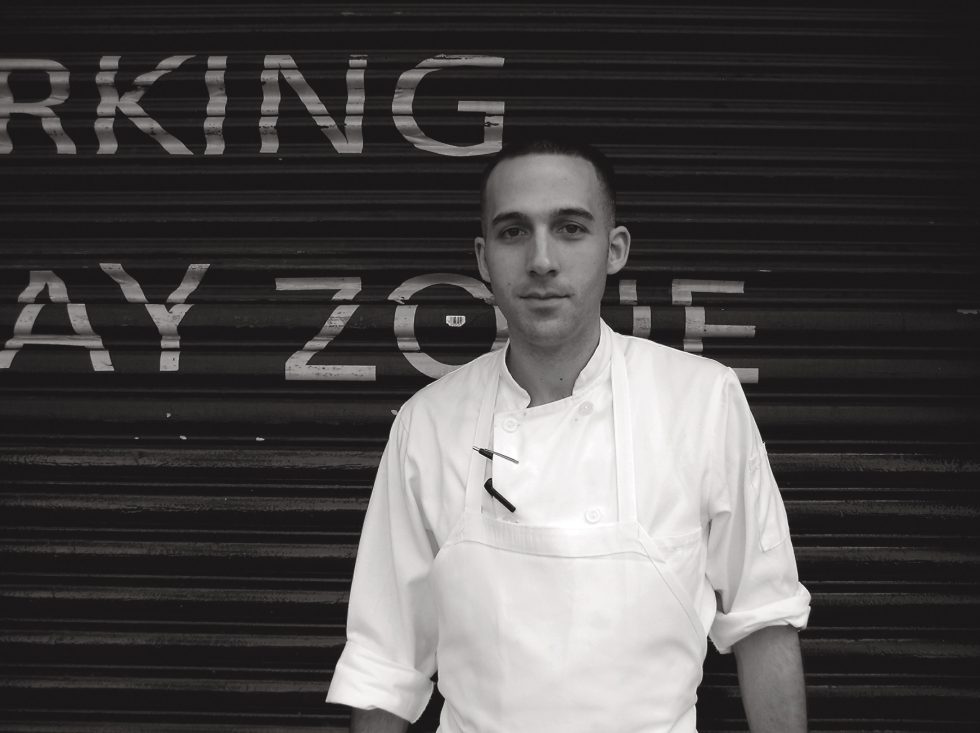 A black and white photograph of a cook having a cigarette outside.