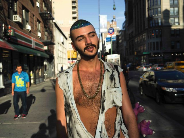 A color photograph of a young man with glitter in his hair.