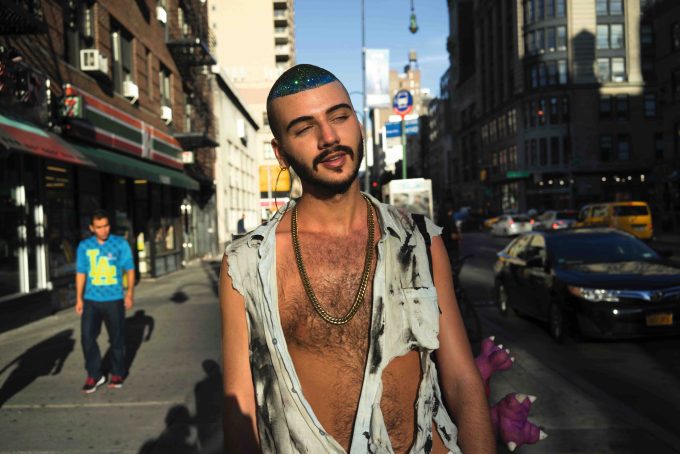 A color photograph of a young man with glitter in his hair.