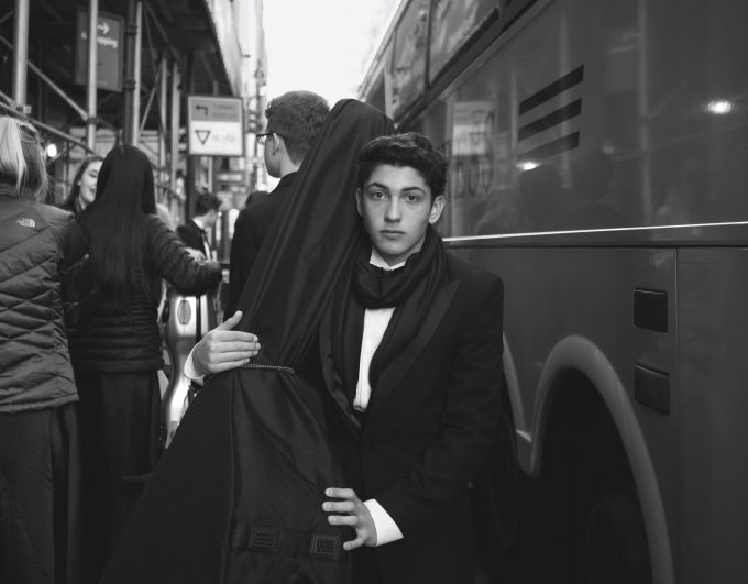 A black and white photograph of a young musician boarding a bus.