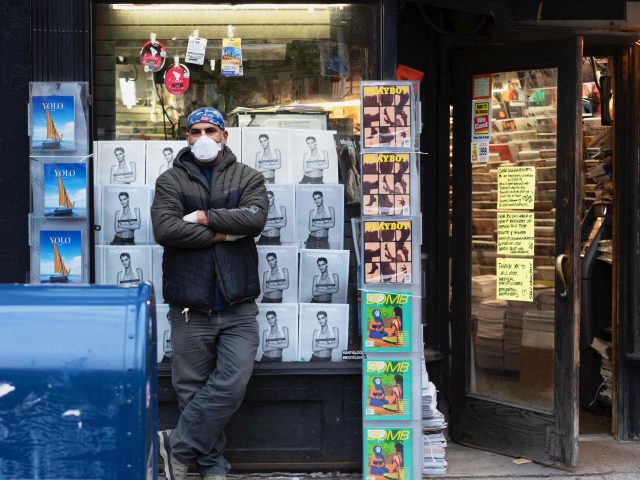 A man standing in front of a magazine store.