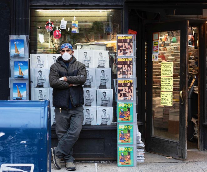 A man standing in front of a magazine store.
