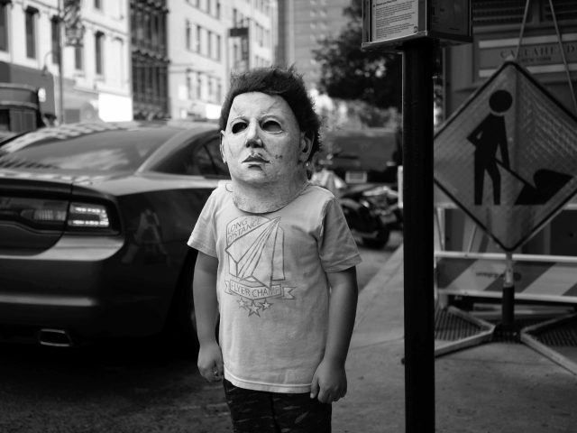 A black and white photograph of a child in a scary halloween mask.