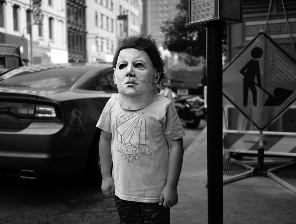 A black and white photograph of a child in a scary halloween mask.