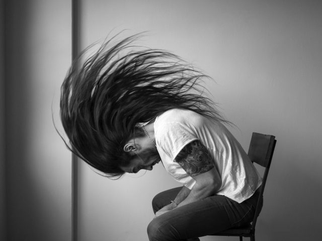 A black and white photograph of a man whipping his hair.