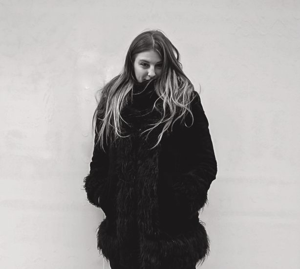 A black and white photograph of a girl in a fur coat.