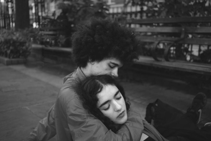 A black and white photograph of a young couple embracing in a park.