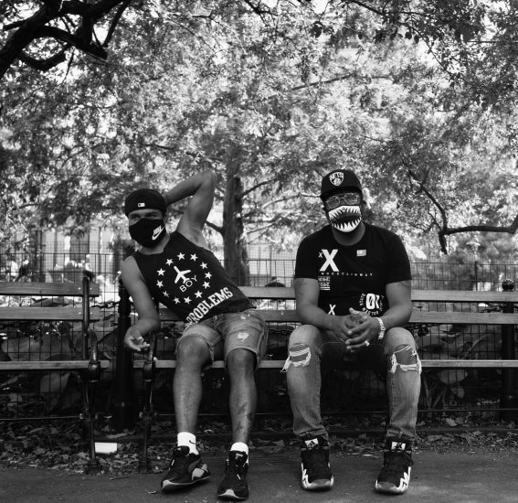 A black and white photograph of two men sitting on a park bench.