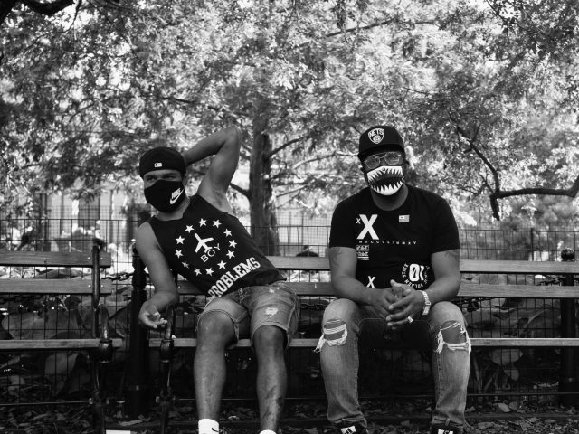 A black and white photograph of two men sitting on a park bench.