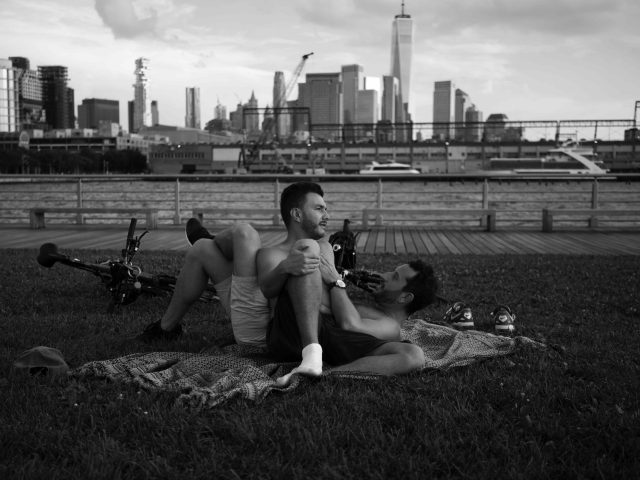 A black and white photograph of two gay men lounging in a park.
