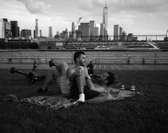 A black and white photograph of two gay men lounging in a park.