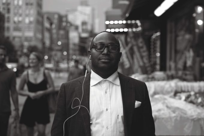 A black and white photograph of a young man, well dressed in a city street.