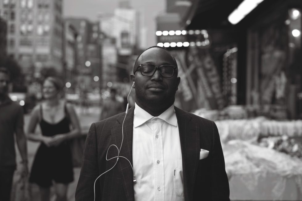 A black and white photograph of a young man, well dressed in a city street.