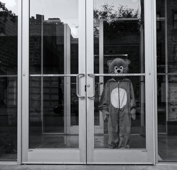 A black and white photograph of a child in costume standing at the entryway to a residence.