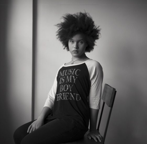 A black and white photograph of a gorgeous young woman sitting in a chair.