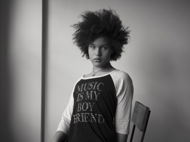 A black and white photograph of a gorgeous young woman sitting in a chair.