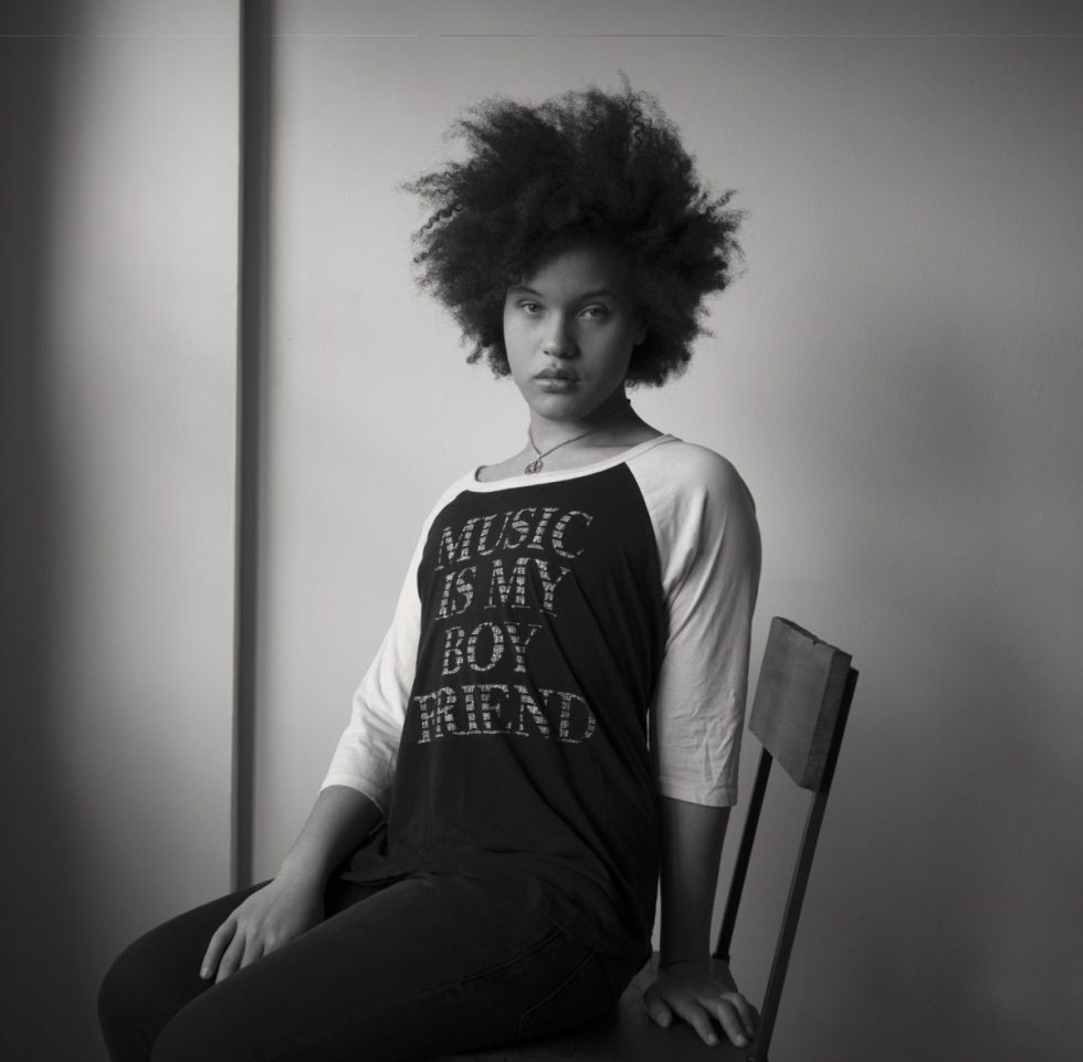 A black and white photograph of a gorgeous young woman sitting in a chair.