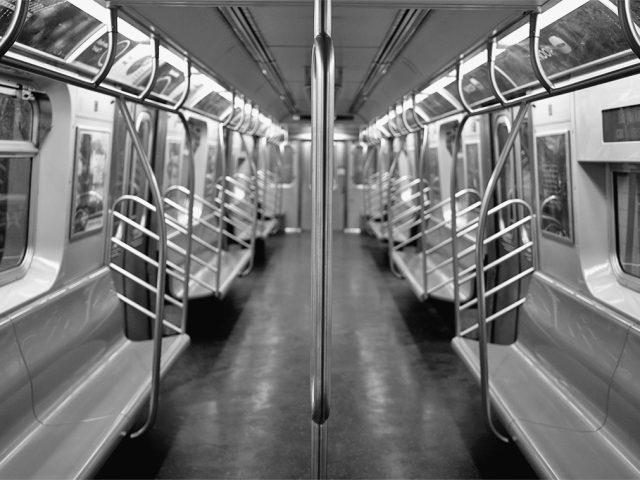 A black and white photograph of a subway train at rush hour.