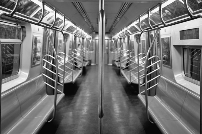 A black and white photograph of a subway train at rush hour.