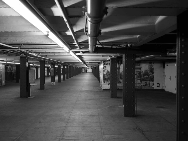 A black and white photograph of an underground subway station.