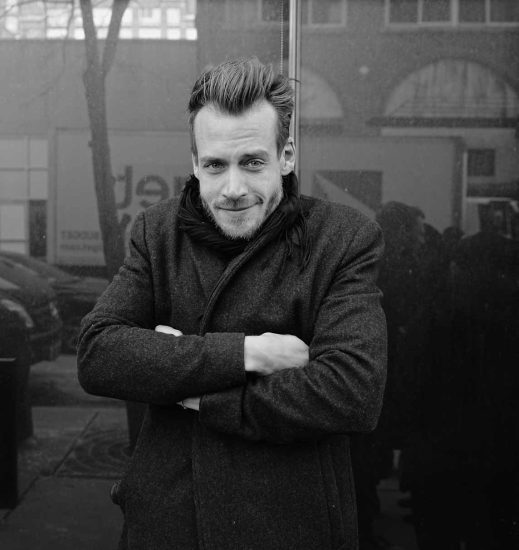 A black and white photograph of a man waiting to get into a fashion show.