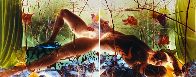 An intense colorful image of a man reclining in the nude among intricate set design.