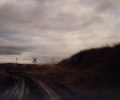A landscape photograph of a dark road and hill with a cloudy sky.