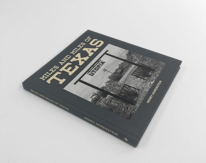 A grey photo book sits on a white surface in even lighting. 
