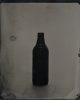 A black and white photograph of an empty glass beer bottle.