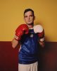 A photograph of a man in a blue tee shirt with boxing gloves.