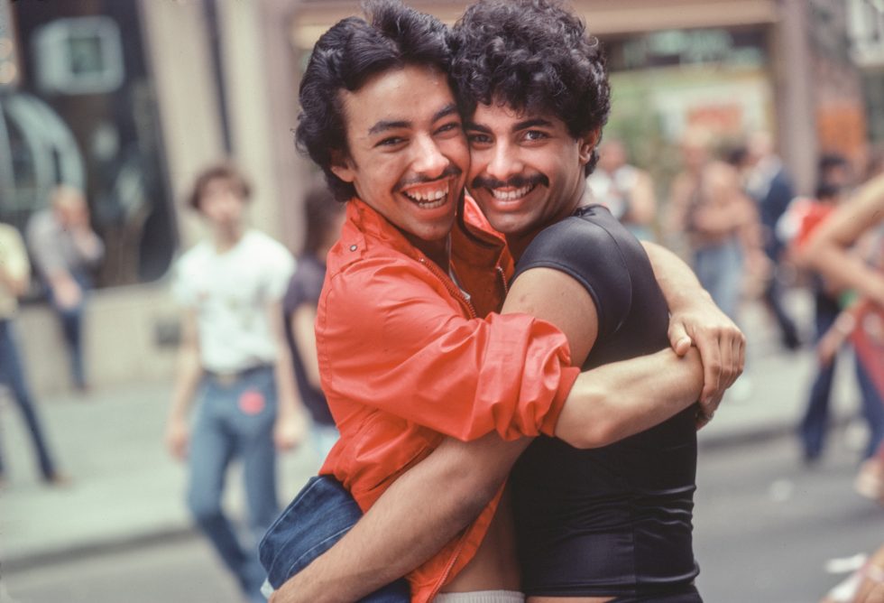 A photograph of two men embracing on a city sidewalk.