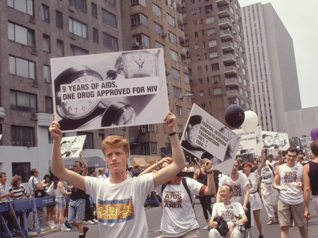 A color photograph of protestors marching through city streets holding signs.