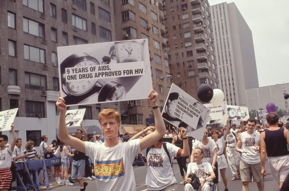 A color photograph of protestors marching through city streets holding signs.