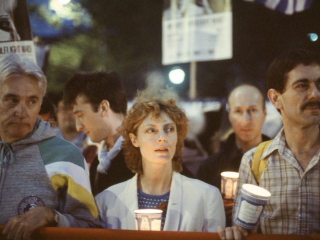 A color photograph of three individuals holding up a banner at a protest.