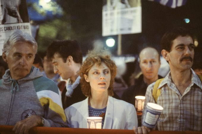 A color photograph of three individuals holding up a banner at a protest.