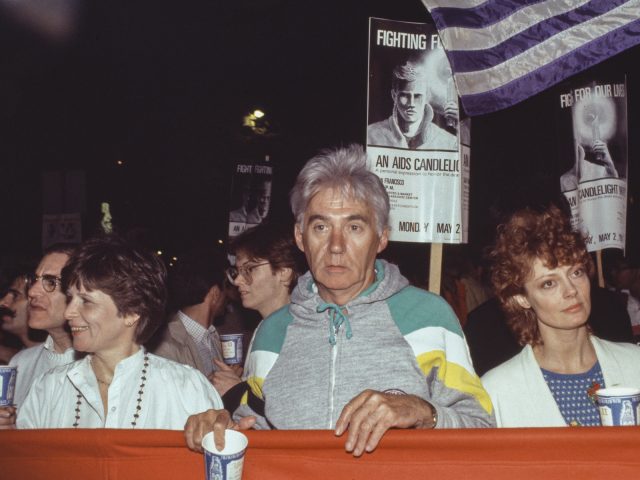 A color photograph of three individuals holding up a banner at a protest.