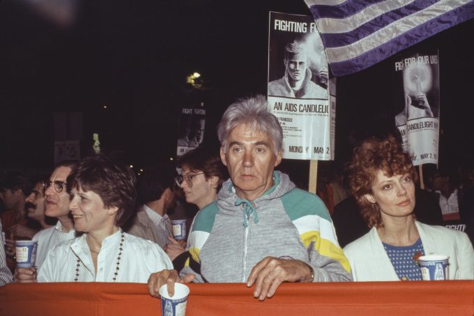 A color photograph of three individuals holding up a banner at a protest.
