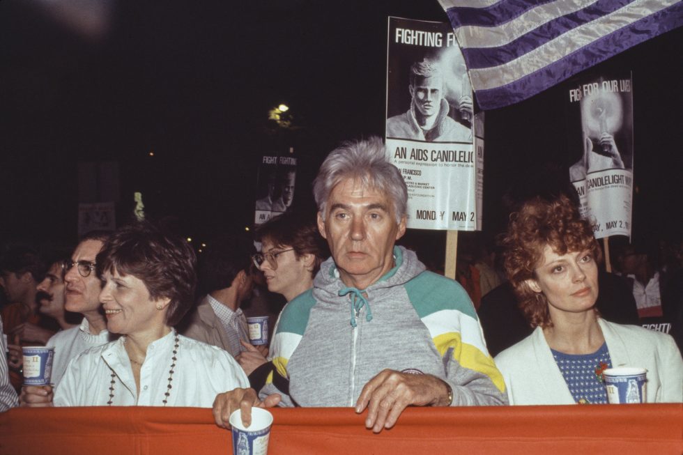 A color photograph of three individuals holding up a banner at a protest.