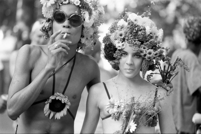 A black and white photograph of two people in floral costumes smoking cigarettes.