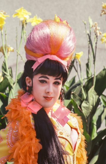A colorful portrait of a woman in a orange and pink costume in sunshine.